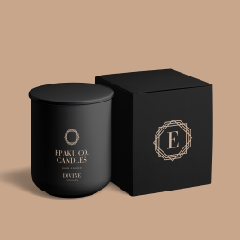 All black candle vessel with Black box. Box is embelleshed with a golden symbol, that has an E in the middle of the symbol. All of this is on a golden beige background