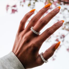 Brown womans hand wearing two amor deus ice rings